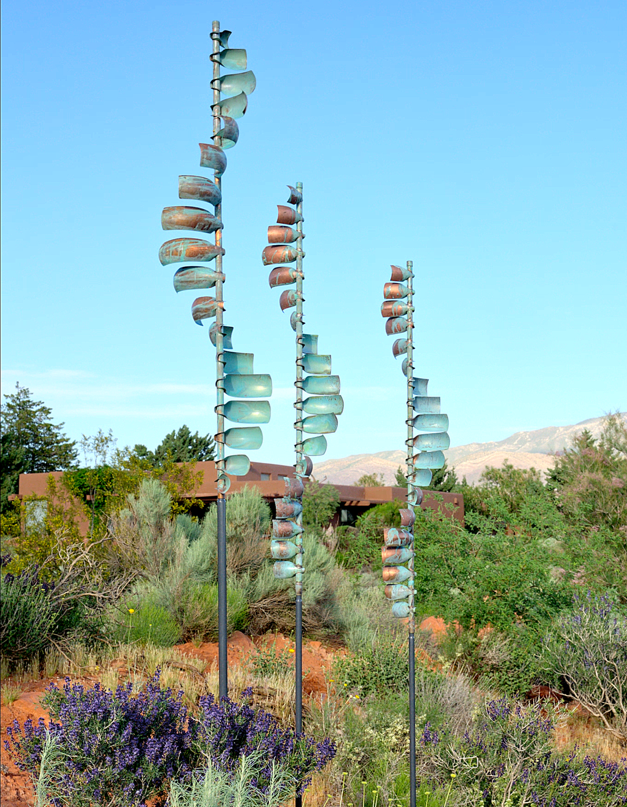Three metal sculptures are standing in a field with purple flowers. AI generated content