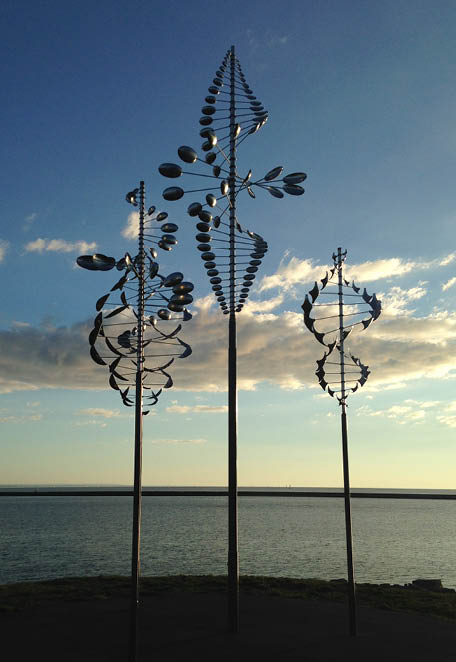 Two wind sculptures are on a concrete base. Description generated by AI