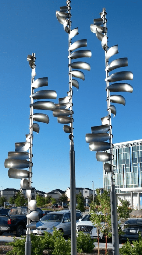 Two sculptures of curved metal are displayed in front of a large building. AI generated content