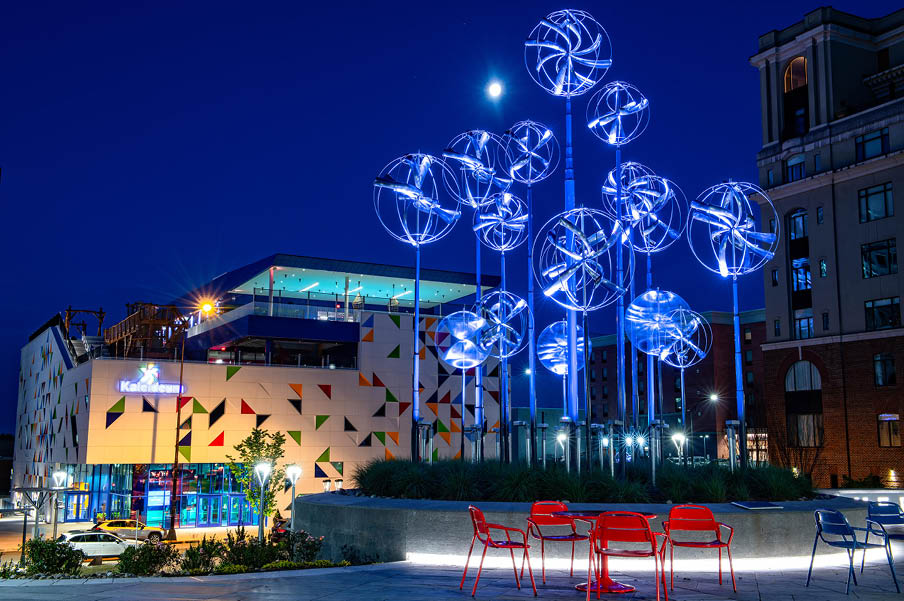 A group of chairs are arranged in front of a building with a blue lighted sculpture. AI generated content