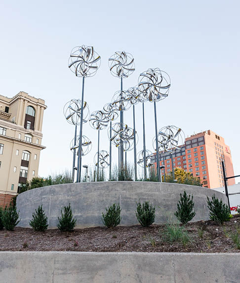 A row of windmills are displayed in a city park. AI generated content