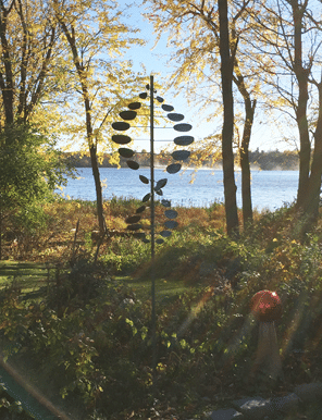 A windmill is located in a garden near a lake. AI generated content