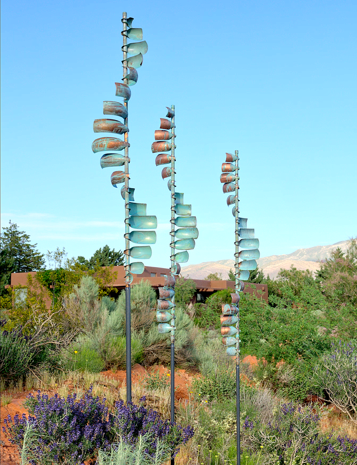 Three metal sculptures are standing in a field with purple flowers. AI generated content